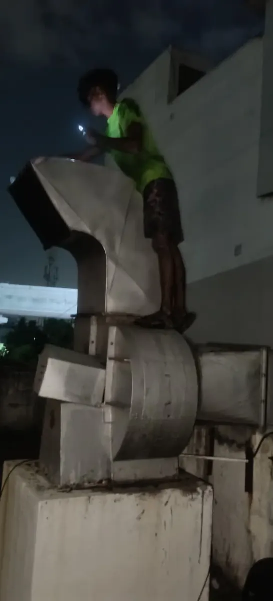 Technician working on a rooftop blower and duct assembly at night