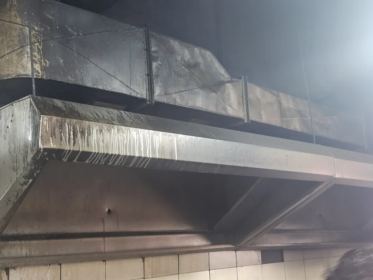 Long stainless steel hood and duct fitted above a cooking line